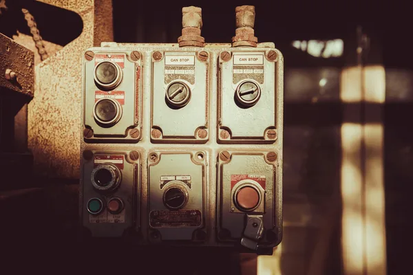 Weathered cast-metal pushbutton and selector stations mounted on a machine