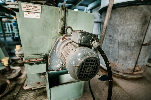 A weathered electric motor mounted on an industrial machine