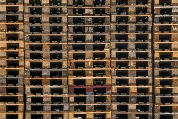 A tall wall of stacked wooden pallets