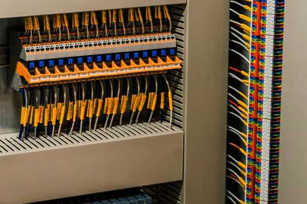 Rows of DIN-rail interface relays and terminal blocks with labeled wires in an open control cabinet