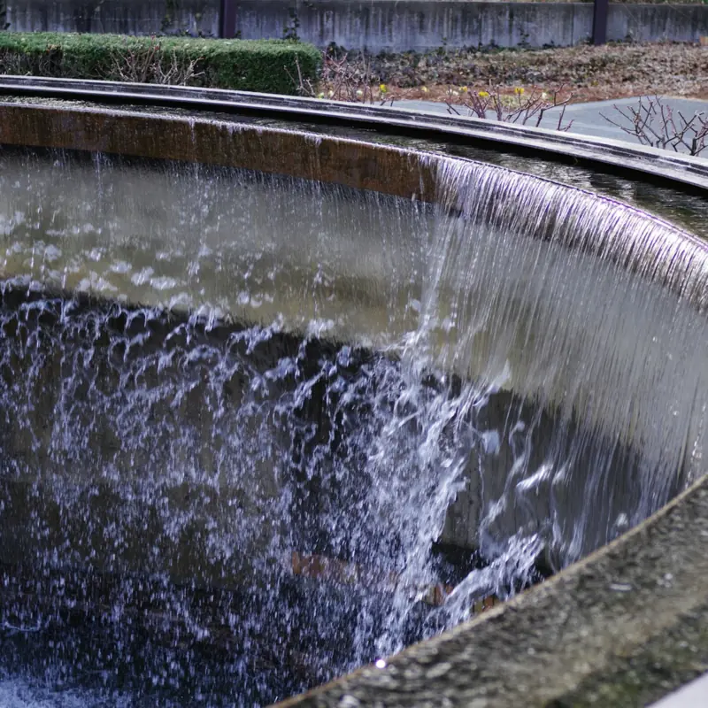 Water spilling over the rim of a round treatment basin