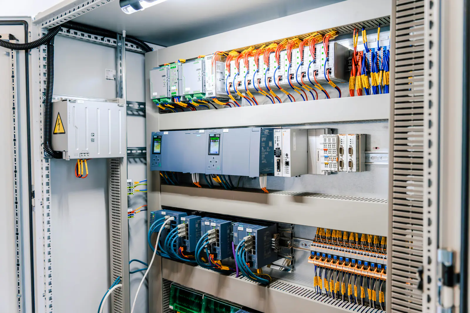 Industrial electrical control panel with PLC modules, power supplies and terminal wiring