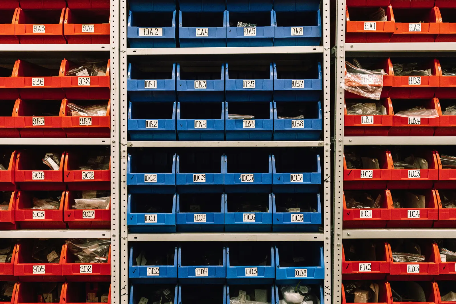 Shelves of red and blue parts bins with location labels
